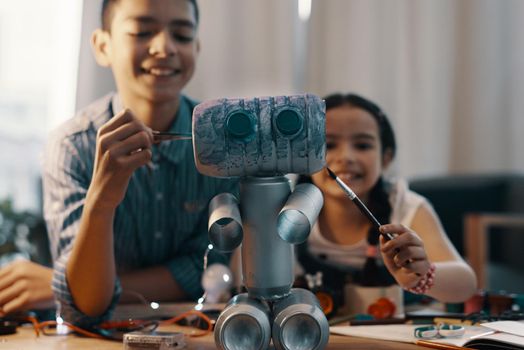 Meet our new friend, Roboboy. Shot of two adorable young siblings painting their newly built toy robot at home.