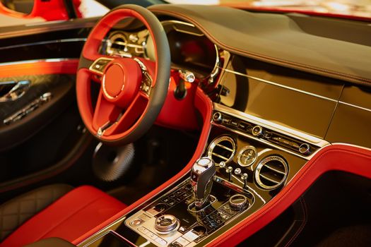 Red luxury car Interior. Steering wheel, shift lever and dashboard. Shallow doff