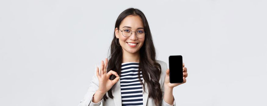 Business, finance and employment, female successful entrepreneurs concept. Close-up of stylish modern asian businesswoman introduce mobile app or advertisement, guarantee quality, show ok sign