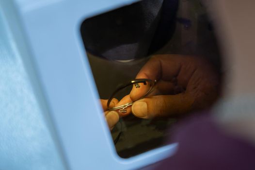 The technician solders the metal frame of the glasses.