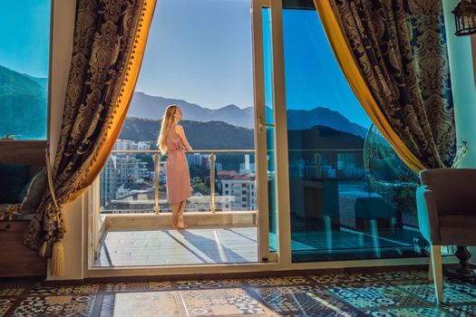 Woman on the balcony against the backdrop of mountains and city, Montenegro. life terrace pretty happiness summer home. Inspiration city romantic hotel