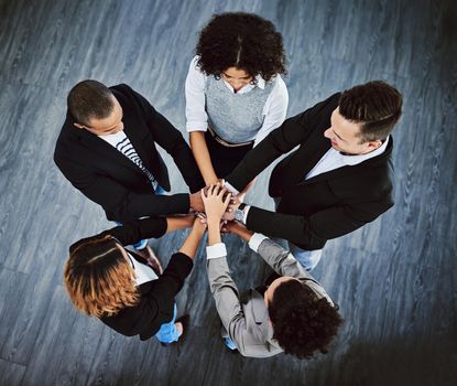 Teamwork allows for the impossible to take place. High angle shot of a group of businesspeople joining their hands together in a huddle.