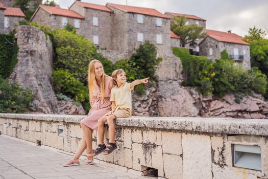 Mom and son tourists on background of beautiful view St. Stephen island, Sveti Stefan on the Budva Riviera, Budva, Montenegro. Travel to Montenegro concept
