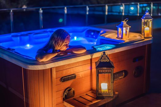 Portrait of young carefree happy smiling woman relaxing at hot tub at night during enjoying happy traveling moment vacation. Life against the background of green big mountains