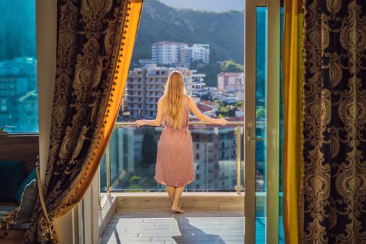 Woman on the balcony against the backdrop of mountains and city, Montenegro. life terrace pretty happiness summer home. Inspiration city romantic hotel