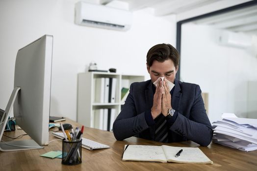 Hes caught the flu. Cropped shot of a businessman suffering with allergies in an office.