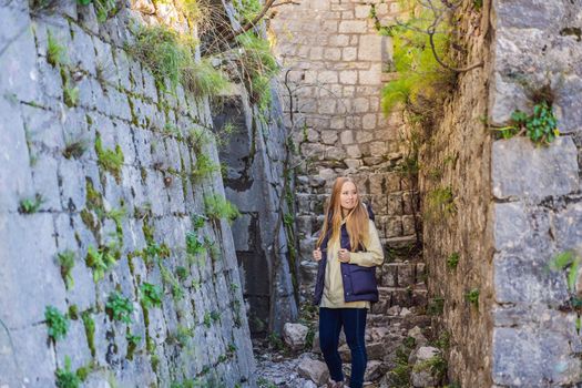 Young tourist woman enjoying a view of Kotor Bay, Montenegro. Kotor Old Town Ladder of Kotor Fortress Hiking Trail. Aerial drone view