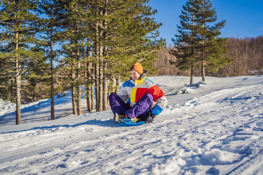 Cheerful man sledding down a snowy slope in full speed
