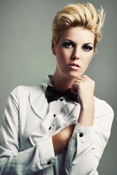 Bringing the bow tie back. Studio shot of a beautiful young woman wearing a shirt and bow tie against a gray background.