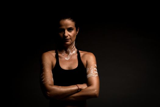 Portrait of a fit girl in sportsbra. Magnesium powder prints of hands on her body..