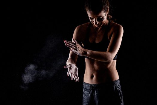 Kickboxer kirl with magnesium powder on her hands punching with dust visible..