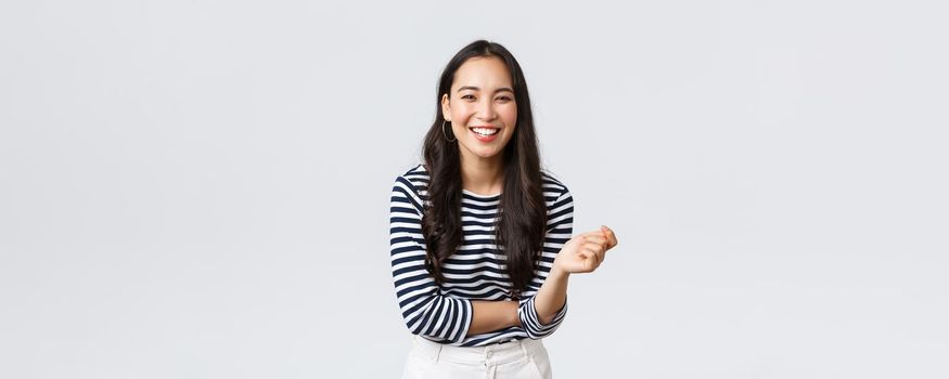 Lifestyle, people emotions and casual concept. Carefree happy outgoing asian woman having fun talking to people, laughing and smiling upbeat, standing white background cheerful.