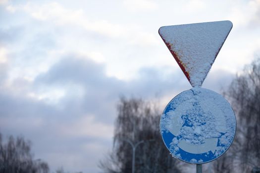 Snowy road sign, intersection with circular traffic.