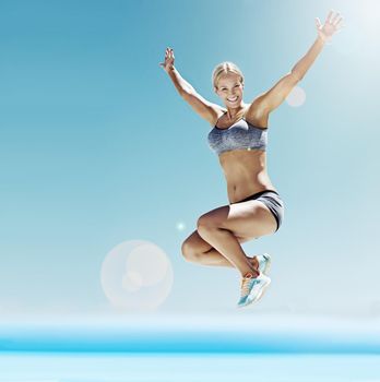 Full of energy and enthusiasm. Shot of a young woman in workout gear jumping in the air.