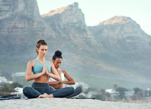 Yoga takes you on a wonderful journey. Shot of two sporty young woman practicing yoga together outdoors.