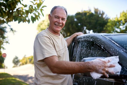 Caring for his car. Portrait of a man washing a car outside.