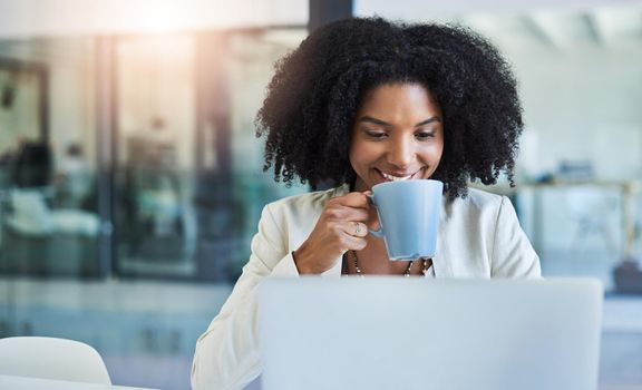 Theres nothing like a cup of coffee to keep you going. Shot of a young businesswoman having a cup of coffee while doing some work at her office desk.