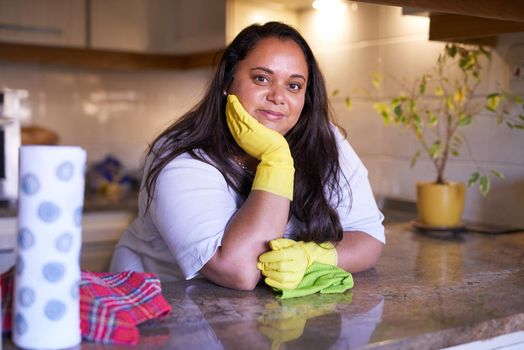 Shes a cleaning whizz. Portrait of a smiling woman leaning on a countertop in a kitchen.