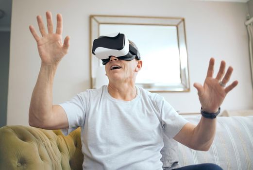 Stepping into another world. Shot of a mature man using a VR headset at home.