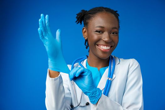 Black female doctor wears sterile blue gloves