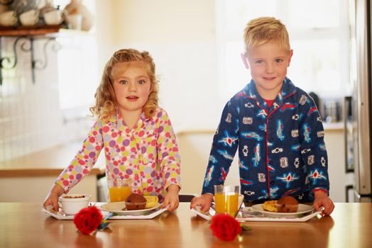 Ready to serve up some yumminess. Portrait of two adorable little siblings preparing breakfast on serving trays at home.