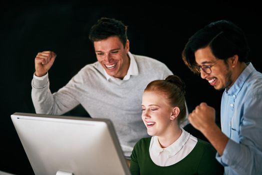 Day or night, we win all the time. Shot of a group of businesspeople cheering while working together in an office at night.