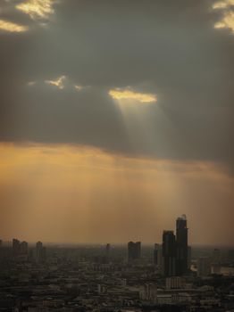The sun's rays passing through the clouds and illuminate skhining down over the skyscraper of bangkok
