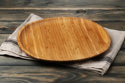 Wooden board with kitchen napkin on dark wooden table