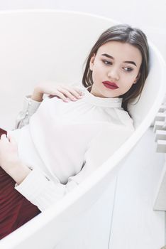 Portrait of fashionable women in red skirt and white blouse posing in a bath