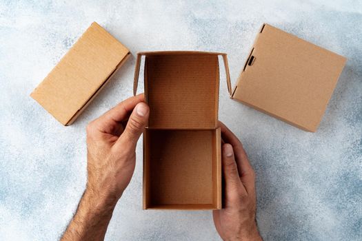 Parcel cardboard box in a man hands on a gray table background
