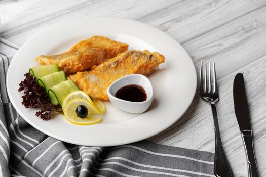 Fried fish fillet and vegetables on white plate
