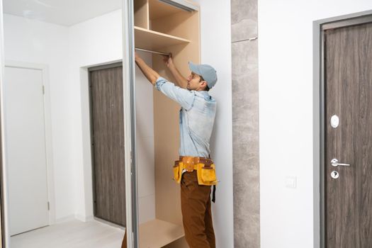 repairman installs a sliding door wardrobe with a mirror