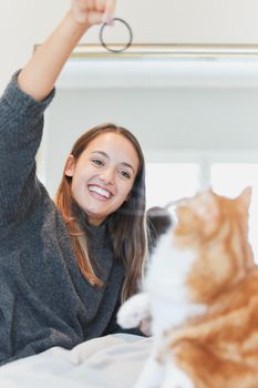 Playing with my cat puts me in the best mood. Shot of a young woman playing with her cat at home.