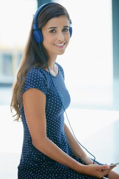 Relaxed tunes to match my mood. Portrait of an attractive young woman listening to music.