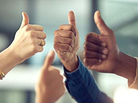 Heres to a job well done. Closeup shot of a group of businesspeople giving thumbs up together.