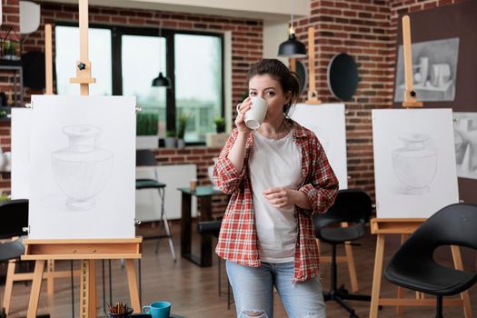 Portrait of art teacher standing in creative workplace drinking coffee