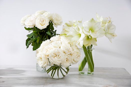 White roses, lily in round vases on the table for a special occasion as a kitchen decoration.