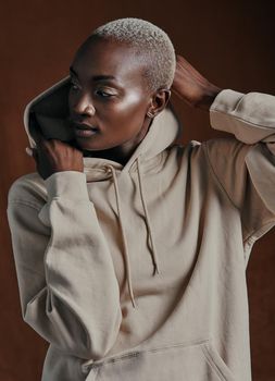 Her soul is fierce, her heart is brave, her mind is strong. Studio shot of an attractive young woman wearing a hoodie and posing against a brown background.