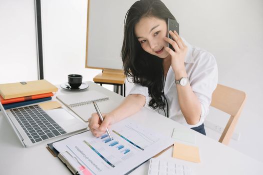 Business woman working with financial document report while talking mobile phone.