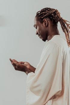 Handsome Young African Muslim Man Making Traditional Fatiha Prayer To Allah God While Wearing A Traditional Sudan fashion clothes in studio