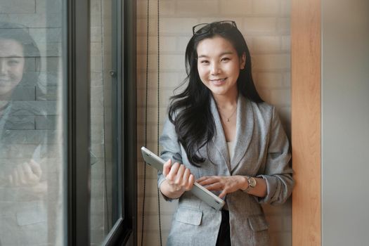 Portrait of smiling millennial businesswoman holding laptop computer looking at camera