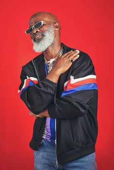 They say Im old but I dont feel od. Studio shot of a senior man wearing retro attire while posing against a red background.
