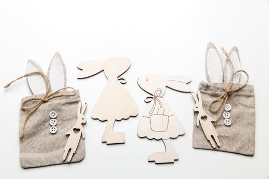 Frame for text. Wooden plywood figures of hares of different sizes, rag canvas bags with ears and buttons, round large beads on a white background