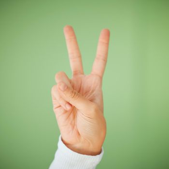 were head bumping to positivity. Shot of an unrecognizable woman showing the peace sign against a green background.