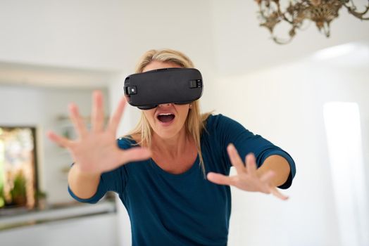 Blurring the lines between fantasy and reality. Cropped shot of a mature woman wearing a VR headset at home.