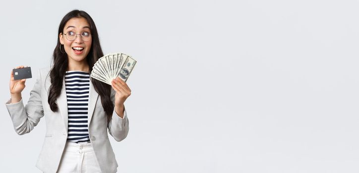 Business, finance and employment, entrepreneur and money concept. Thoughtful successful female office manager, employer thinking how invest cash, holding dollars and credit card