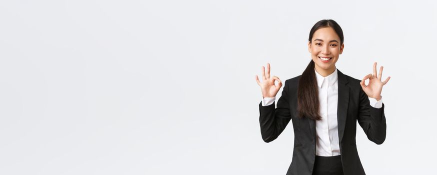 Professional pleasant saleswoman showing okay gesture, selling house. Pleased businesswoman finish good deal showing ok, approval sign and smiling satisfied, standing white background