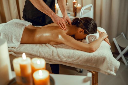 Half naked relaxed woman getting back spine massage at beauty spa resort. Treatment