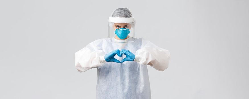 Covid-19, preventing virus, health, healthcare workers and quarantine concept. Doctor saving life patient from coronavirus pandemic, show heart sign, wear personal protective equipment, PPE costume