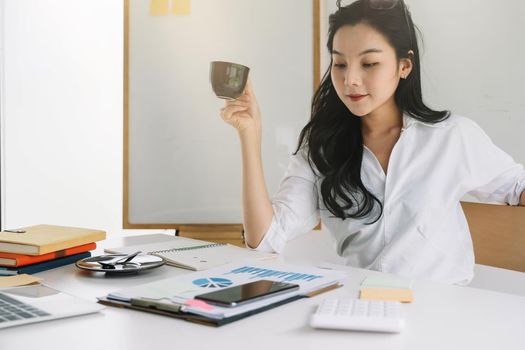 Young asian entrepreneur cogitating thinking making important decision at workplace. Concentrated serious office worker millennial woman analysing results